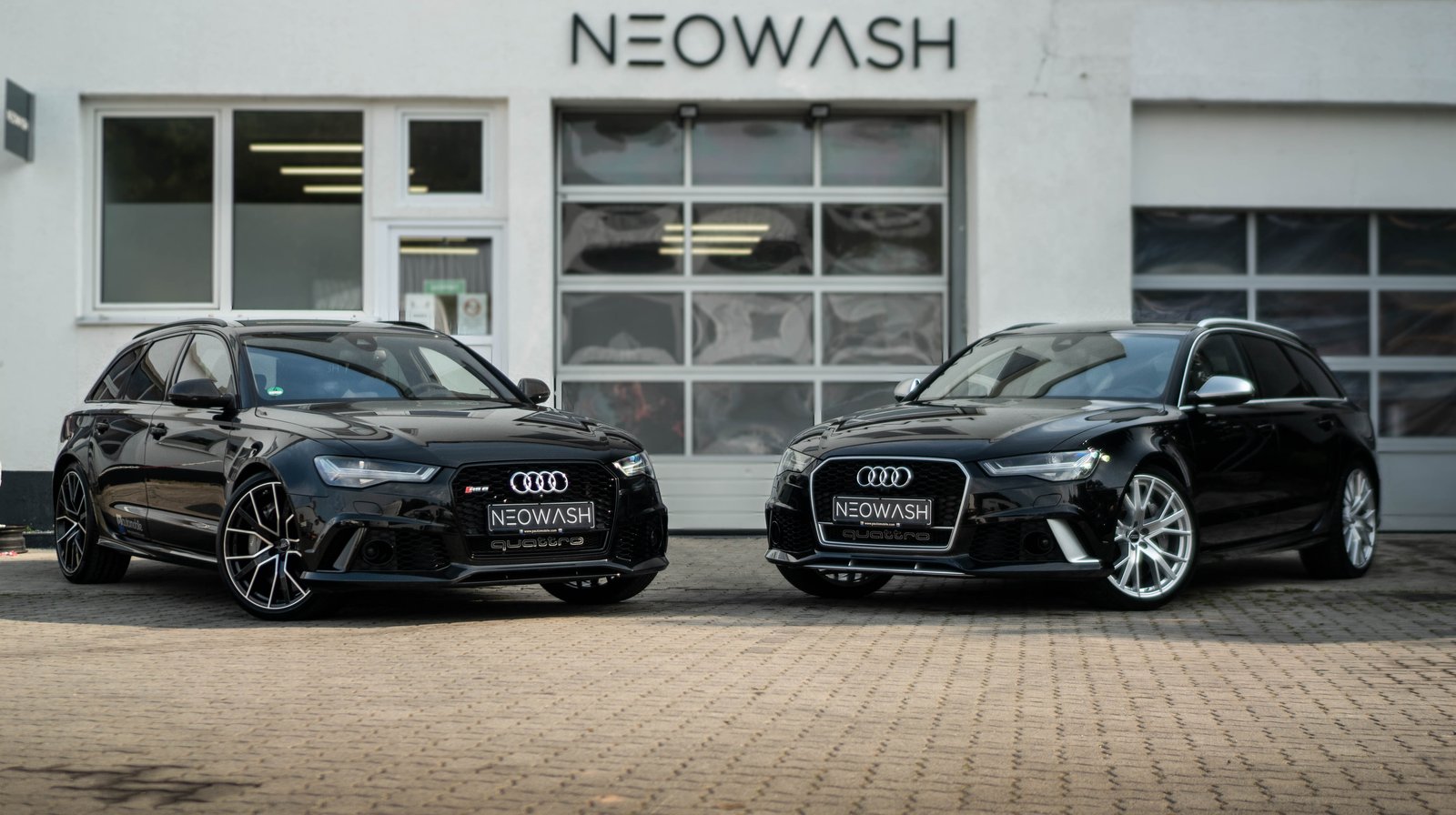 Zwei schwarze Audi RS6 Avant nebeneinander vor dem Neowash Studio in Braunschweig — Premium-Fahrzeuge im Partnerverbund
