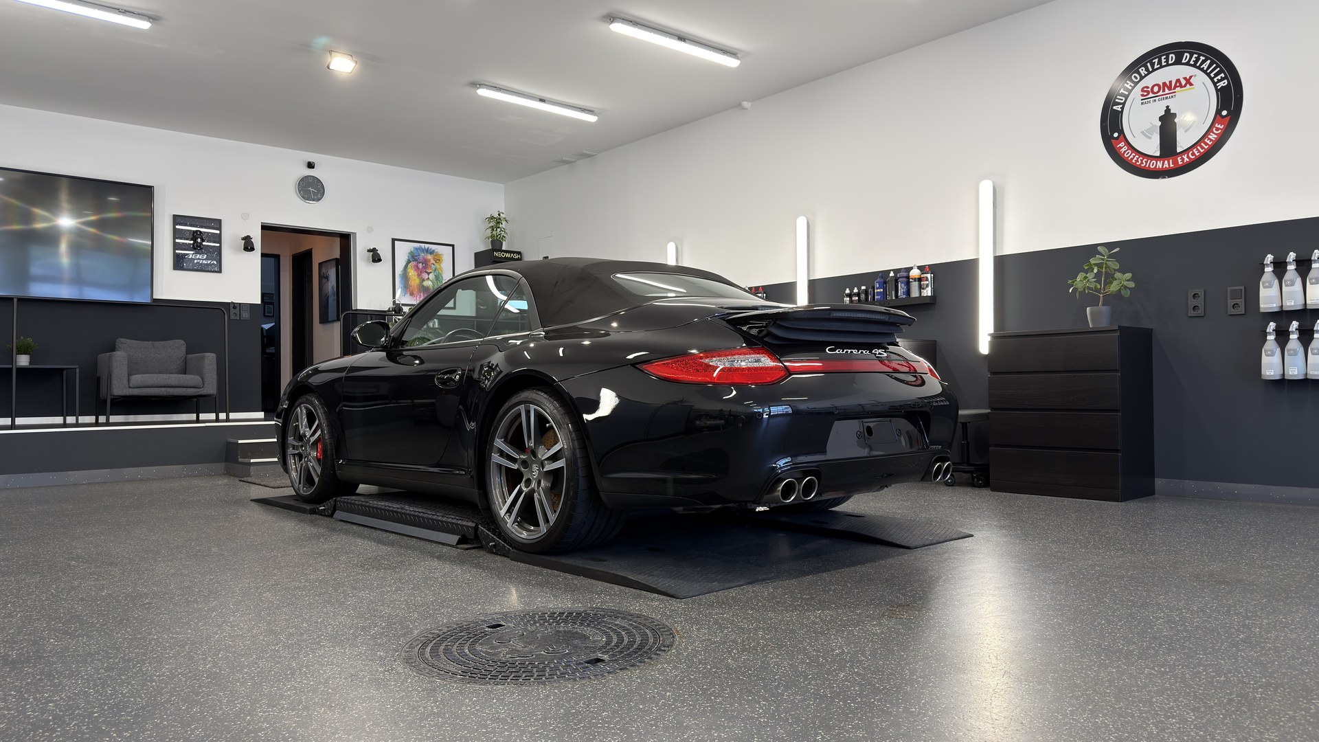 Premium-Detailing Studio Neowash Braunschweig: schwarzer Porsche 911 Carrera 4S Cabrio im Detailing-Studio mit Sonax Authorized Detailer Plakette