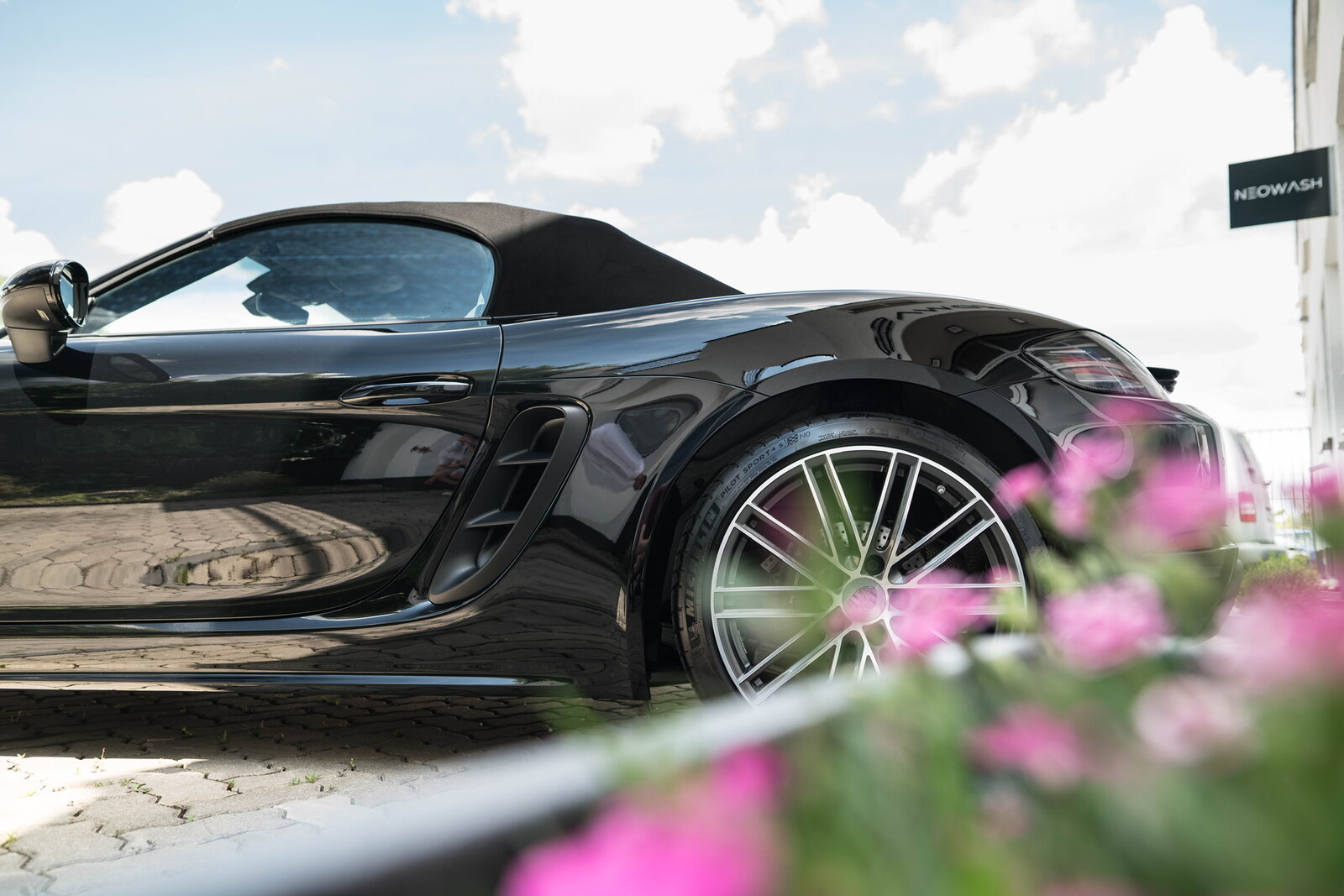 Schwarzer Porsche 718 Cabrio vor dem Neowash Detailing-Studio in Braunschweig mit NEOWASH-Schild im Hintergrund