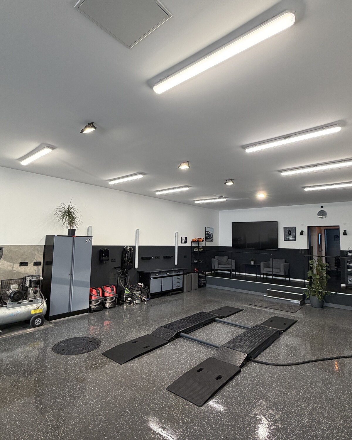 Innenraum des Neowash Detailing-Studios in Braunschweig — Werkstatt mit Auffahrrampen, polierter Bodenbeschichtung und Premium-Pflegeprodukten